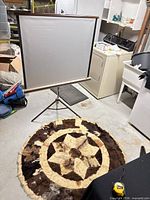 Projector screen on tripod next to round patchwork hide rug