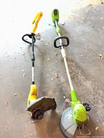 Overall view of both string trimmers on garage floor