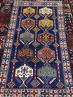 Full view of navy blue wool Goochan carpet with multicolour geometric design