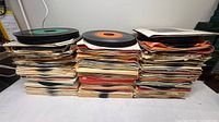 Three tall stacks of 7-inch vinyl singles with sleeves and loose discs