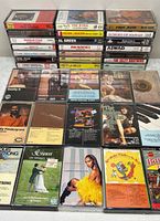 Overall shot of stacked and laid-out cassette tapes showing quantity and variety