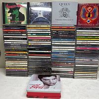 Front view of full lot: four featured CD covers on top row, two tall stacks of CD spines beneath, Elvis tin in foreground
