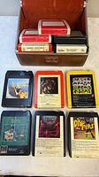 Open brown carrying case with eight 8-track cartridges displayed