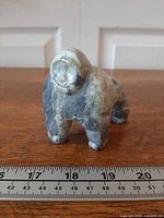 Front angled view of stone bear behind metric ruler for scale
