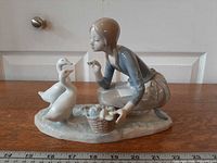 Front view of figurine showing girl, two ducks, basket