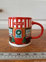 Front view of mug with storefront design and ruler showing height
