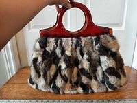 Front view of handbag showing faux fur pattern and handle
