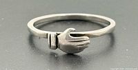 Front view of sterling silver ring showing hand clasp design