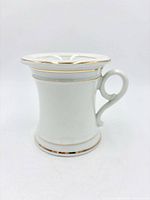 Side view of porcelain scuttle mug showing handle and gold banding
