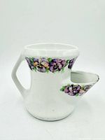 front view of white ceramic scuttle mug showing side spout and floral decals