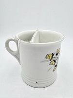 Side view of ceramic scuttle mug showing handle, floral decoration and base