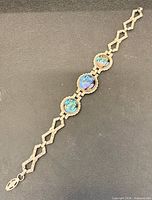 Full view of bracelet laid flat, showing length, three cabochons and geometric links