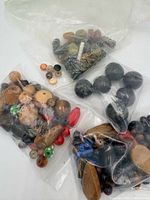 Four bags of assorted beads displayed on surface