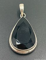 Front view of teardrop pendant showing faceted onyx and silver bezel
