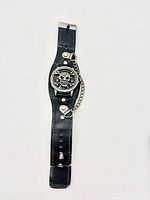 Full view of black leather cuff watch with skull face and chain