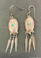 Front view of both earrings showing turquoise cabochons, stamped ovals and feather drops
