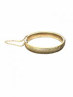 Side view of sterling silver hinged bangle showing floral engraving and safety chain