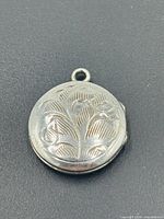 Front view of sterling silver round locket with floral engraving