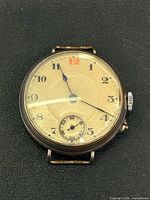 Front view of trench watch displaying dial, hands and numerals