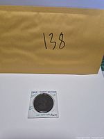 Coin in holder with envelope showing lot number