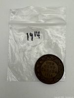 Reverse side of 1914 Canadian cent beside labelled bag