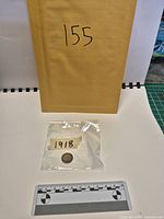 Coin in plastic sleeve with year label and scale