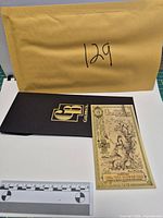 Front of 2022 Utah 1 Goldback note with sleeve and scale for size