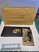 Goldback note with sleeve and reference scale