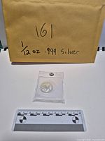 Coin in plastic sleeve with scale and envelope showing labeling