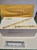 closed box with labels indicating bulk common Pokémon cards not English