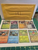All eight sleeved Pokémon cards laid out in two rows