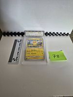 Full shot of graded Pikachu card in slab with rulers and lot tag
