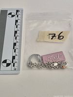 Bracelet in plastic bag beside metric scale