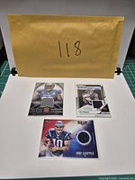 Overview of three sleeved football memorabilia cards with envelope ID