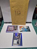 Overview of three memorabilia football cards with envelope showing lot number