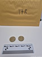 Envelope, ruler for scale, two tokens front view