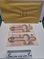 Fronts of both $2 notes showing Queen Elizabeth II portraits and serial numbers