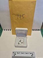 Overview of box with rings inside, envelope for scale