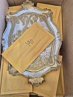 Top view of ornate white-and-gold Florentine tray in box