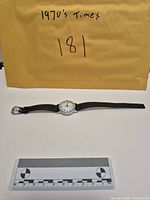 Full view of Timex wristwatch laid flat with scale