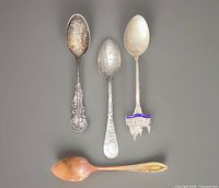 Front view of four souvenir spoons showing designs and colors