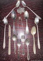all flatware pieces and chains laid out on dark wood surface