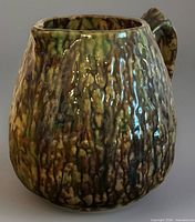 Front angled view of green and brown textured stoneware pitcher