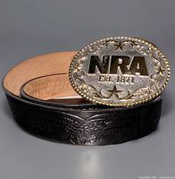 Buckle attached to coiled belt showing silver face, gold edge, belt tooling