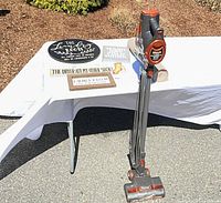 Full lot showing Shark Rocket vacuum beside table with signs and liner roll