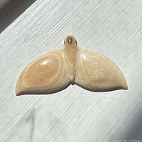 Front view of polished bone whale tail pendant