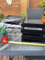 All four stands, two wrapped in plastic, one fully assembled shown with tape measure for scale