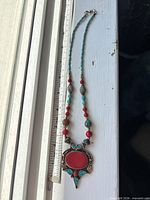 Full necklace beside ruler showing length and pendant design
