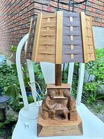 Front view of lamp showing carved figures and woven slat shade