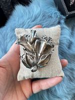 Front view of silver-tone floral brooch showing three trumpet flowers and leaves